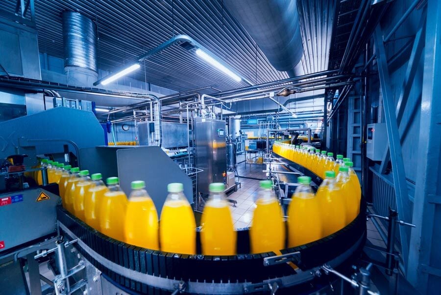 orange juice being bottle in a factory enviorment