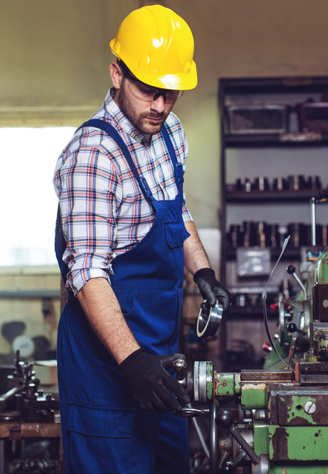 Milling machine operator working in factory workshop - cropped